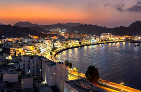 A stunning panoramic view of the illuminated Mutrah Corniche and harbor area at sunset, showcasing...