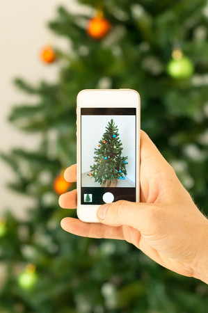 Hand taking photo of Christmas tree by smartphone.の写真素材