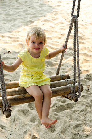 Little girl swinging with the beach in the background.の写真素材