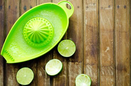 green limes with green manual juicer on the table.の写真素材