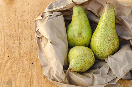 Delicious pears in brown paper on wooden table.の写真素材