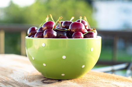 Green bowl full of ripe cherry. Selective focus.の写真素材