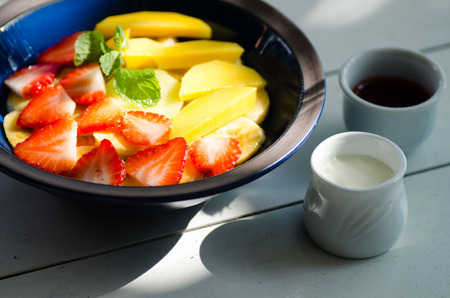 Clay bowl with fruit salad. Yogurt and honey in glass bottleの写真素材