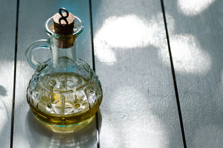 Small glass jar with oil on white wooden table. Space for text.