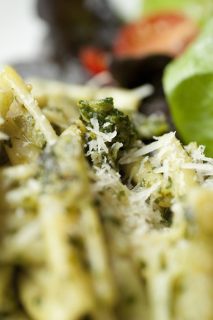Pasta Dish with Green Pesto and Salad on a White Plateの写真素材