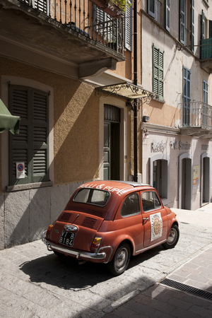 A classic red Fiat 500 car parked in a traditional Italian street near Lake Como, Lombardy, Italy - 29th August 2011のeditorial素材