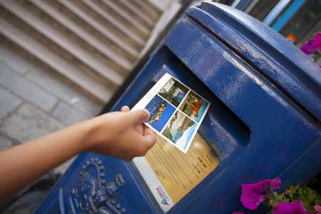 a Hand putting a postcard in a Blue Guernsey Post Box unique to Guernsey in the town of St Pierre Port (St Peter Port), the main settlement of Guernsey, The Channel Islands, UK - 11th July 2013のeditorial素材