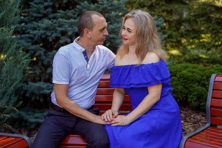 Happy young couple in love sitting on a park bench. Concept of happy family. life style.の写真素材