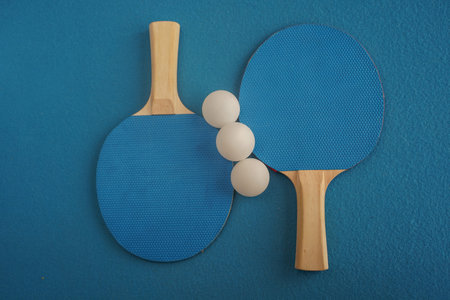 Two blue table tennis  rackets lie on a blue background with a close-up view from above. Game for leisure. sport equipment. international competition. table tennis. healthy lifestyleの写真素材