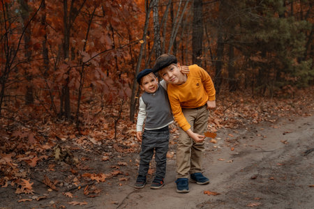 Cute brothers of school and preschool age pose in the autumn forest in retro style. Advertising of children's fashionable clothes.の写真素材