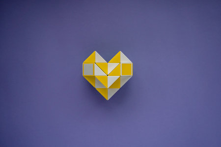 Puzzle toy folded in the shape of a heart. Valentine's Day background with heart. Very Peri background color 2022. Flat lay, copy space. The concept of love, happy family, wedding, fidelity.の写真素材