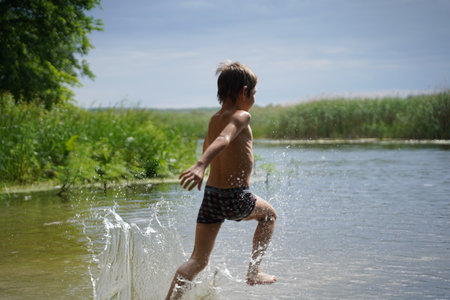 Happy child boy running on beach on summer holidays. Kid boy playing outdoors on nature. selective focus.の写真素材