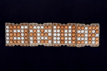 The inscription EASTER is lined with brown eggs top view. Hundreds of white eggs in paper trays. Original Easter business concept.の写真素材