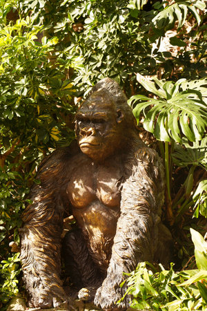 A bronze monkey sits in the bushes. The concept of recreation and tropical travel. protection of...