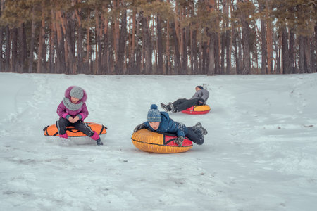 Children and parents have fun riding from the snowy mountain on tubing. Group of children sliding...