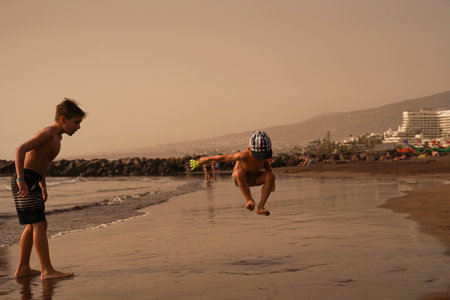 Children have fun on the seashore, splashes in all directions. Happy Summer Holiday. A fun holiday. Family Sea Vacationの写真素材
