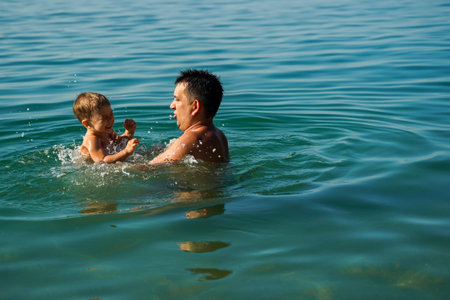 Dad and son splashing in the water merrily. Summer family holidays.の写真素材