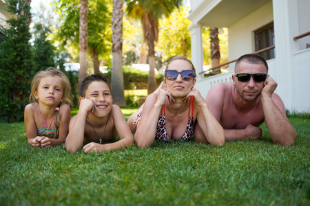 A happy family lies on the grass in a tropical paradise. Summer family vacation. bottom view