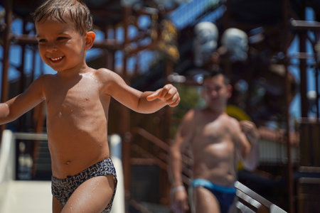 A child happily runs away from his dad on a summer vacation in a water park. family holidays. Taking a vacation at the hotelの写真素材