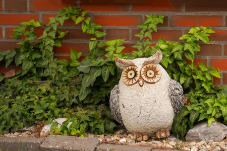 Stone owl in a flower bed. Original garden figure and decorationの写真素材
