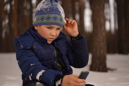 A business boy reads disturbing stock market reports in between winter entertainments. The child...