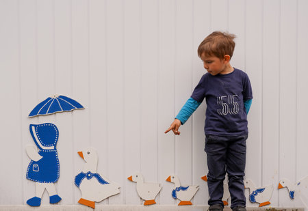 Child posing against the wall with decorative ducksの写真素材