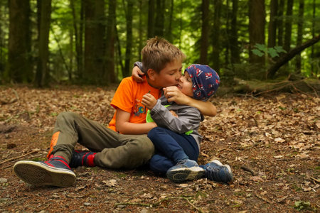 Little boy hugging and kissing his brother, children in the forest. happy familyの写真素材