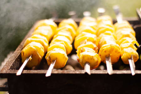 photos of delicious potatoes on skewers in the grillの写真素材