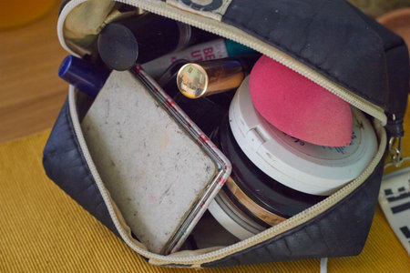 Unbuttoned black cosmetic bag with cosmetics. Mirror, posada, sponge, shadows, eyeliner, blush. makeup. Women.の写真素材