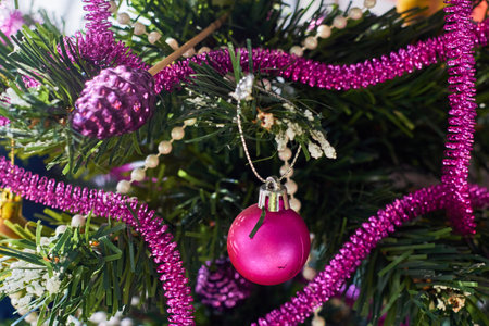Decoration of an artificial Christmas tree for the holiday. Pink plastic ball and pink tinsel. new year.の写真素材