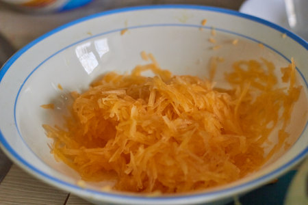 Photo of pumpkin pulp grated on a fine grater. In a white ceramic bowl. Benefits of vegetables. Health food. baby food. Vegetarianism. raw food.の写真素材