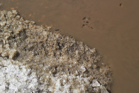 Abstract background of a melted mud puddle and remnants of snow. The color of cocoa. offroad.の写真素材