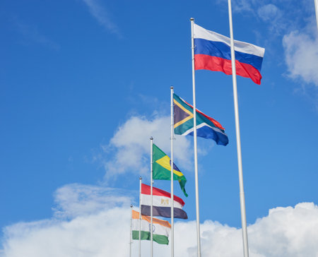 Multiple national flags fluttering against a blue skyの写真素材