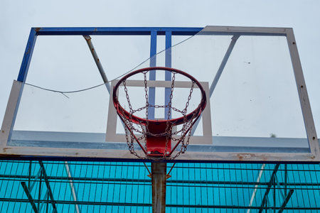 A broken basketball hoop with a board and a chain that is not well attached