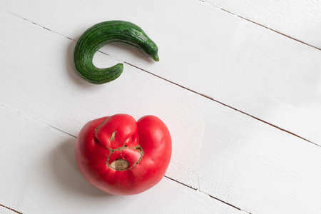 Ugly vegetables cucumber and tomato on white wooden backgroundの写真素材