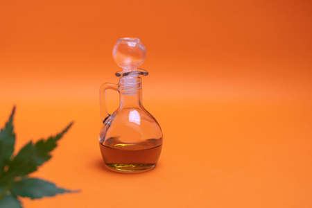 Raw cannabis oil in a glass bottle on orange backgroundの写真素材