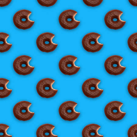 Seamless pattern with bitten chocolate glazed donuts (doughnuts) on blue backgroundの写真素材