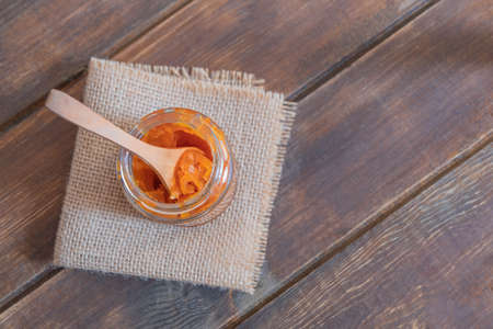 Freshly made carrot jam in a glass jar on wooden table. Image with copy space, top viewの写真素材