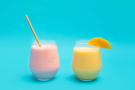 Traditional indian Mango Lassi and Strawberry Lassi drinks in glass cups on blue backgroundの写真素材
