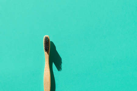Eco-friendly bamboo toothbrush made from biodegradable materials on green paper background. Zero...