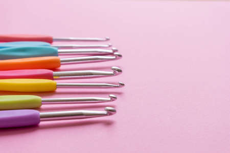 Closeup image of different size colorful crochet hooks on soft pink backgroundの写真素材