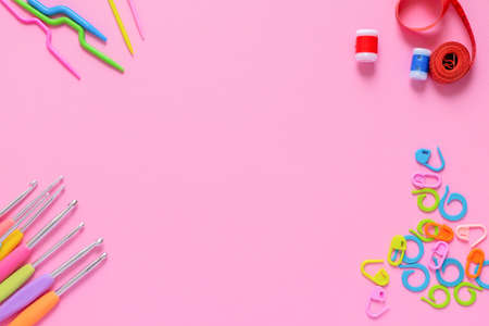 Colorful crocheting and knitting accessories on soft pink background with copy spaceの写真素材