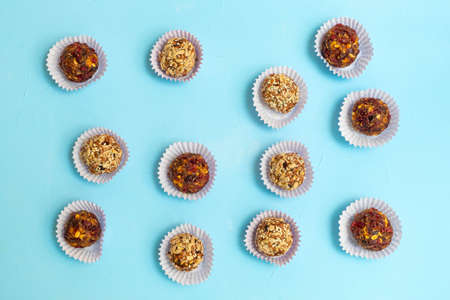Various energy balls made of dried dates and nuts on soft blue background.