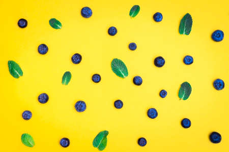 Fresh ripe blueberry with mint leaves on yellow background. Blueberry patternの写真素材