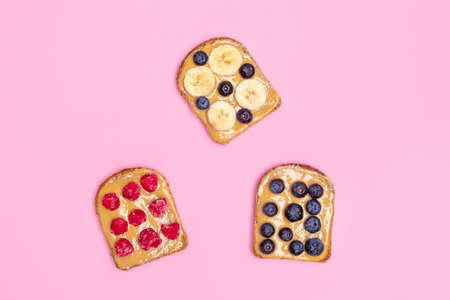 Directly above view of peanut butter toasts with berries and banana on pastel pink background, flat layの写真素材