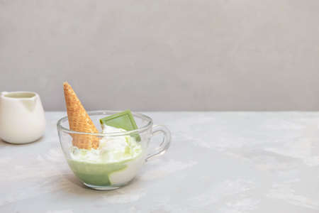 Matcha affogato recipe with vanilla ice cream and healthy matcha green tea in a glass cup on grey...