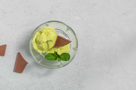 Top view of healthy natural avocado ice cream with mint leaves and chocolate pieces on neutral...