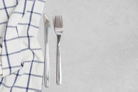 Fork and knife silverware with napkin on neutral concrete background. Above view, space for textの写真素材
