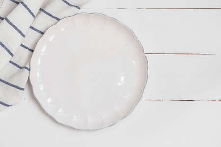 Empty white plate with napkin on white wooden table. Top view with space for text, mockupの写真素材