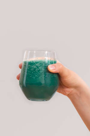Woman hand holding cup of spirulina smoothie on neutralの写真素材